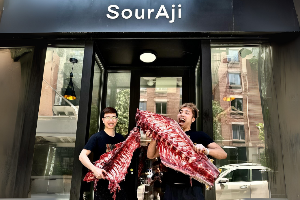 SourAji founders Xu Lu and Jake Weng carrying whole beef racks outside the East Village storefront